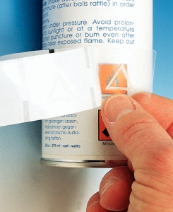 Hand die ein Warnsymbol für Blinde auf eine Spraydose klebt