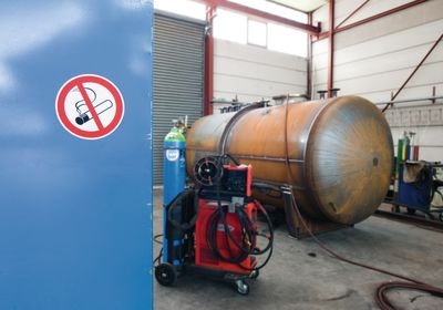Verbotsschild mit brennender Zigarette klebt an der Tür vor dem Kessel