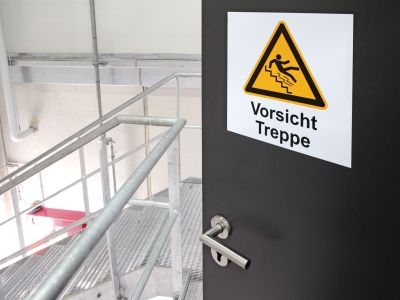 Tür mit Warnschild 'Vorsicht Treppe'