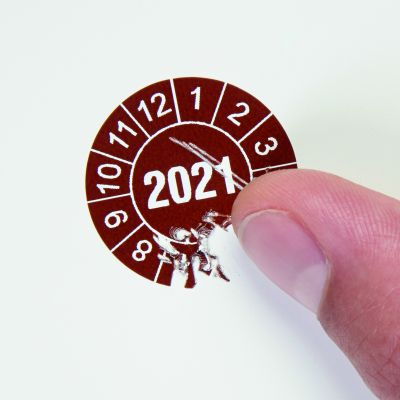 Materialbild zeigt den Versuch die Plakette vom Objekt abzulösen und die Dokumentenfolie zerreißt in kleine Stücke